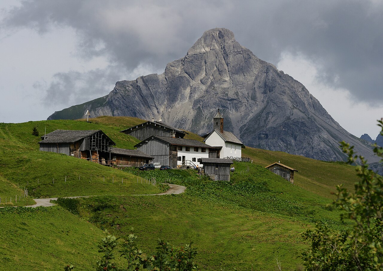 Almgebäude und Kapelle vor einem mächtigen Berggipfel